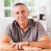 Happy man sitting at table in kitchen